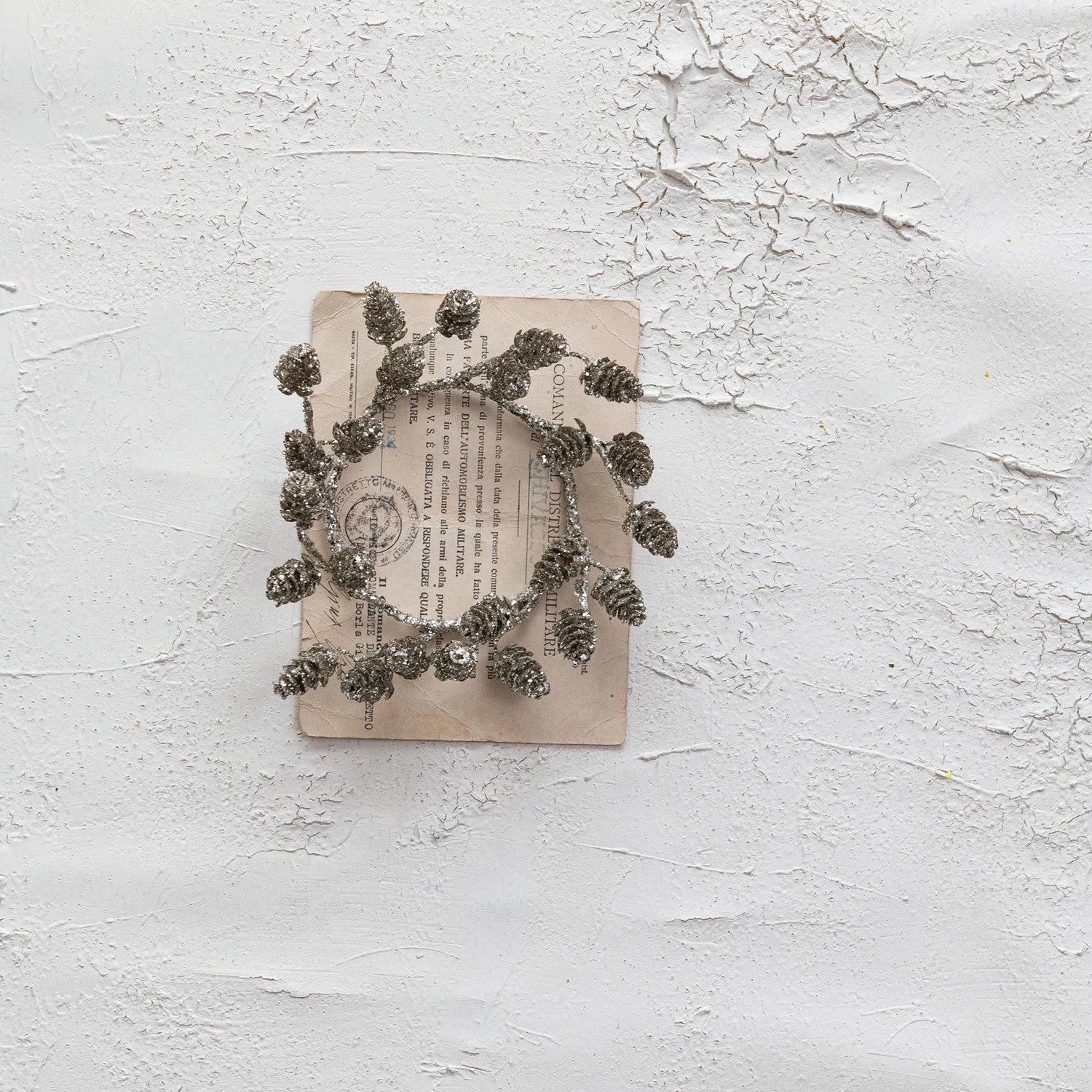 Decorative wreath made of pine cones on an old book with a textured white background