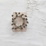 Decorative wreath made of pine cones on an old book with a textured white background