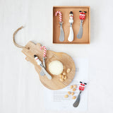 Set of four cheese knives with decorative handles on a wooden board with a white background