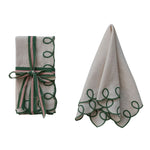 Two beige napkins with green decorative patterns on a white background