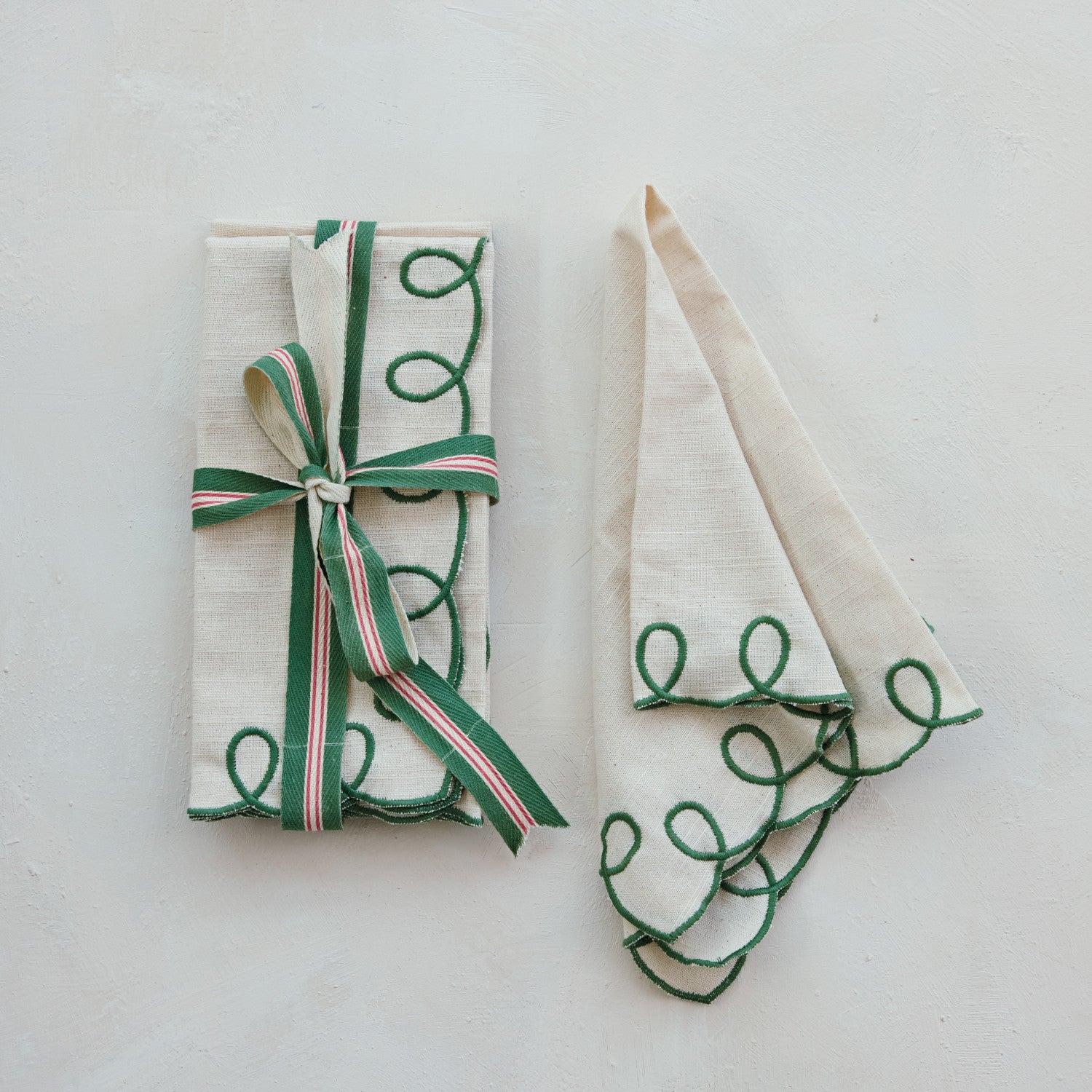 Two folded towels with green embroidered designs on a white background