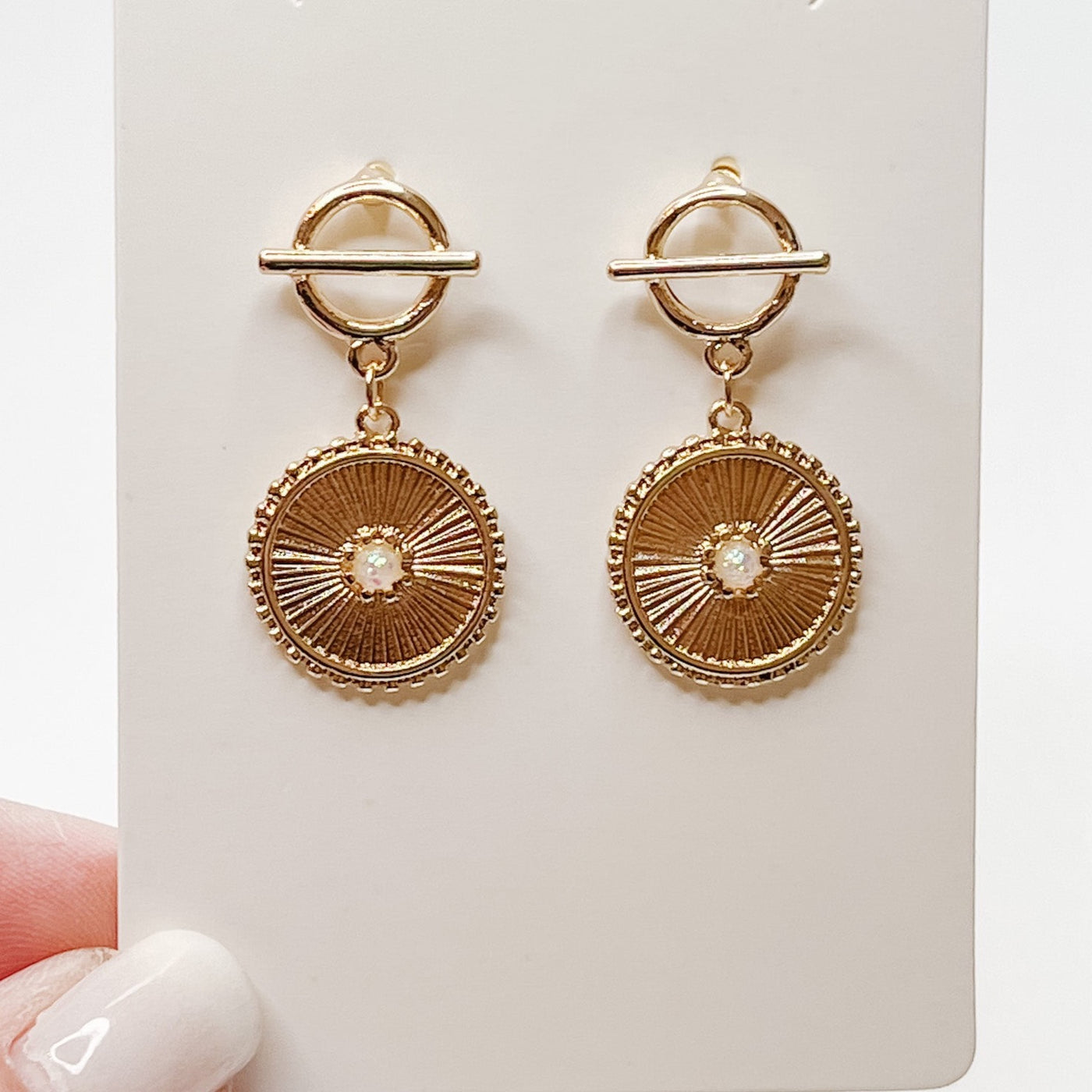 gold dangle hoops with an opal centered in a textured gold circular charm